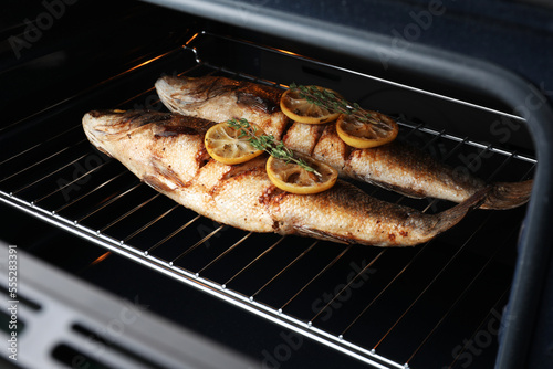 Rack with sea bass fish, lemon and thyme in oven