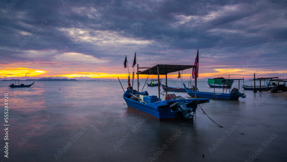 Small fishing boat with fishing net and equipment by the beach during sunrise