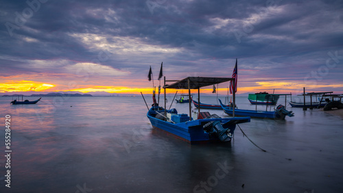 Small fishing boat with fishing net and equipment by the beach during sunrise