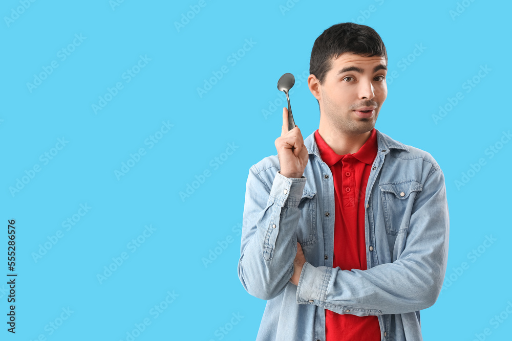 Young man with tablespoon on blue background Young man with tablespoon on blue background