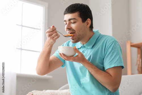 Young man eating cornflakes...