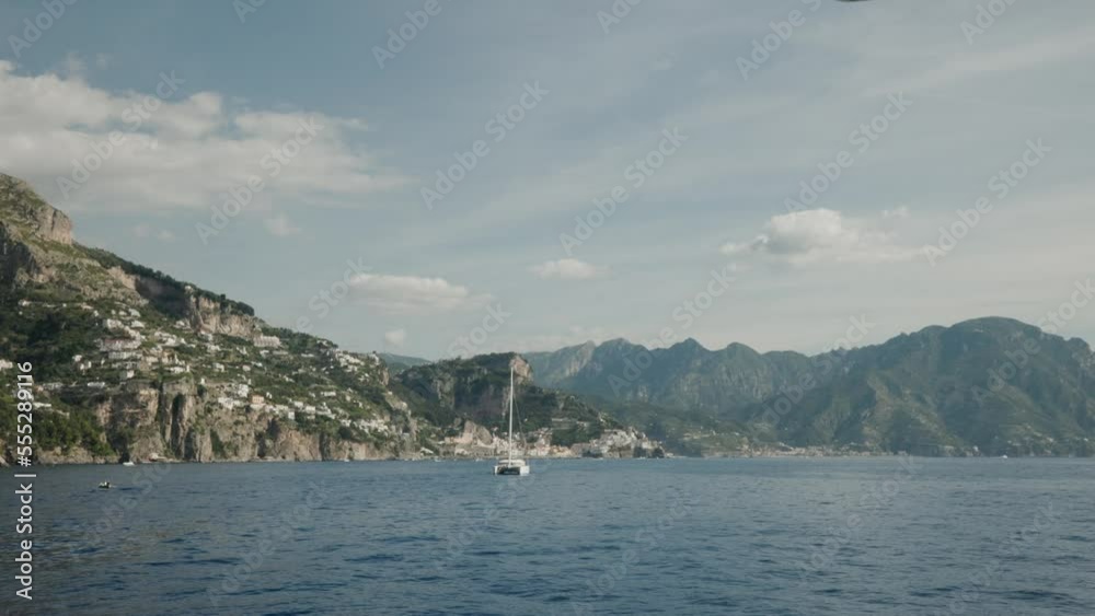 Catamaran Sailboat And Mountainous Surroundings On The Amalfi Coast In Italy. wide Catamaran Sailboat And Mountainous Surroundings On The Amalfi Coast In Italy. wide
