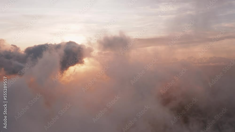 Incredible heavenly aerial view flying through light, heaped up and wispy clouds in golden sunset, sunrise revealing sun. Forward motion. 4k footage.