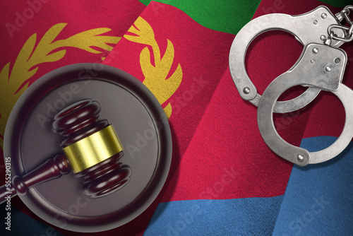 Eritrea flag with judge mallet and handcuffs in dark room. Concept of criminal and punishment, background for guilty topics photo