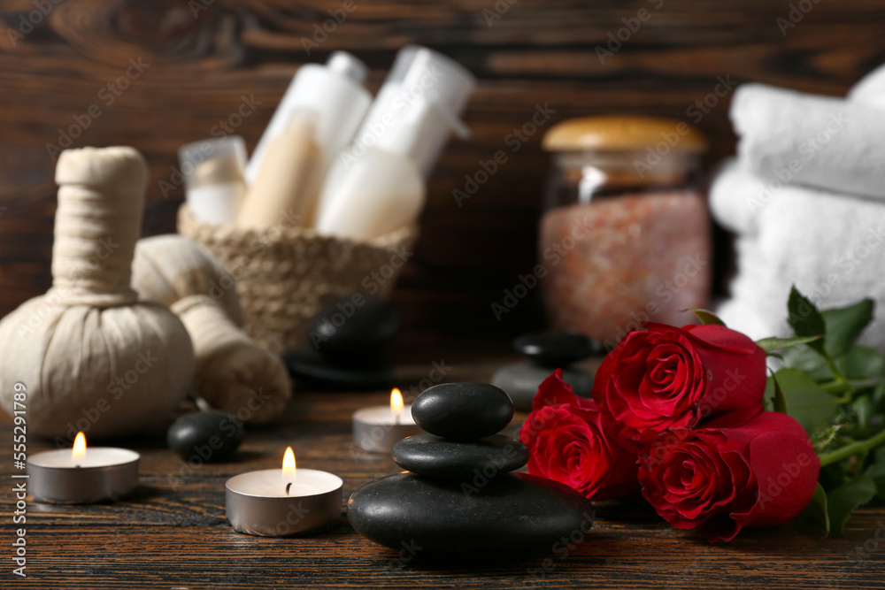 Beautiful spa composition for Valentine's Day with stones, candles and rose flowers on wooden background Beautiful spa composition for Valentine's Day with stones, candles and rose flowers on wooden background