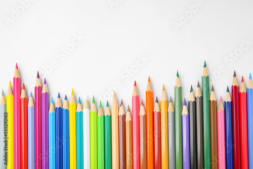Many colorful wooden pencils on white background, flat lay. Space for text