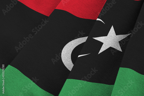 Libya flag with big folds waving close up under the studio light indoors. The official symbols and colors in fabric banner photo