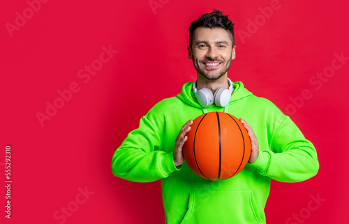 smiling man holding basketball ball studio. Basketball player smiling isolated on red.