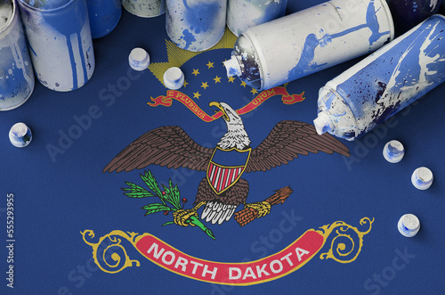 North Dakota US state flag and few used aerosol spray cans for graffiti painting. Street art culture concept, vandalism problems photo