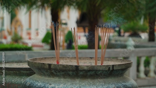 Close-up of a sandalwood incense stick slowly smoldering and releasing fragrant smoke into the air in temples. Incense sticks as a symbol of Buddhist ritual and oriental religion and faith. photo