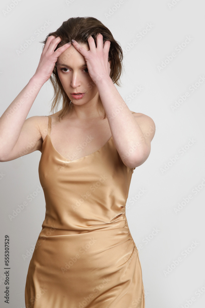 Woman in golden silk satin camisole dress, studio shot. Woman in golden silk satin camisole dress, studio shot.