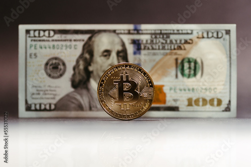 bitcoin coin with 100 dollar paper bill in the background