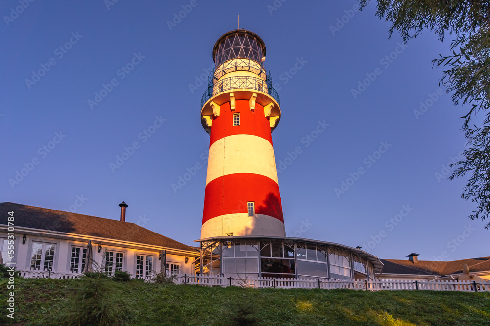 The lighthouse is traditionally painted with white and red stripes against a blue sky.