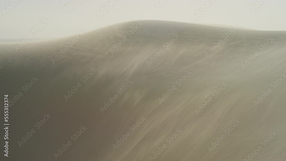 Wide panning shot on windy white sand dunes on stormy day