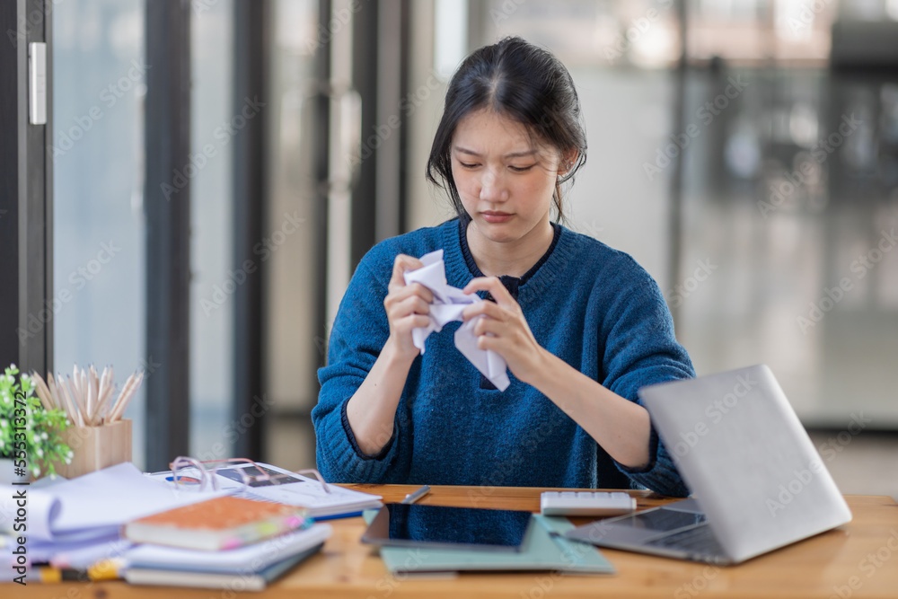 Fototapeta premium Portrait of tired young business Asian woman work with documents tax laptop computer in office. Sad, unhappy, Worried, Depression, or employee life stress concept.