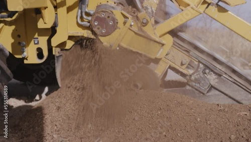 Close up real time shot of dirt flying from trencher machine on construction site photo