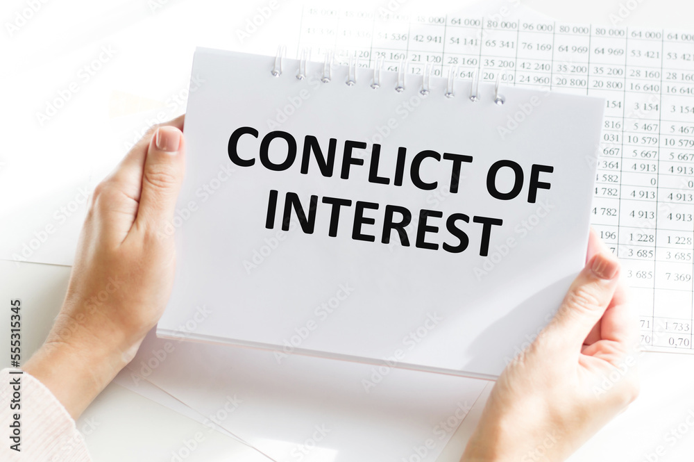 Male hand writing 'conflict of interest' on white note, isolated on white background. Business concept, copy space. Male hand writing 'conflict of interest' on white note, isolated on white background. Business concept, copy space.