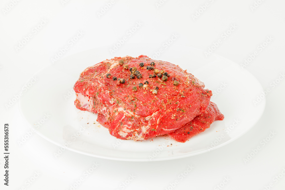 Red marbled raw steak on a white plate. Red marbled raw steak on a white plate.
