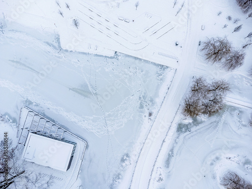 Aerial view. Winter landscape. Snow, frost, paths, trees, park, white powder.