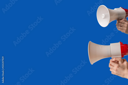 Megaphone in woman hands on a blue background.