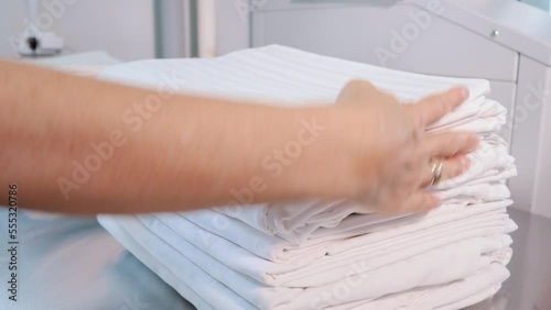 Large pile of bed linen. Women's hands neatly fold the sheets.