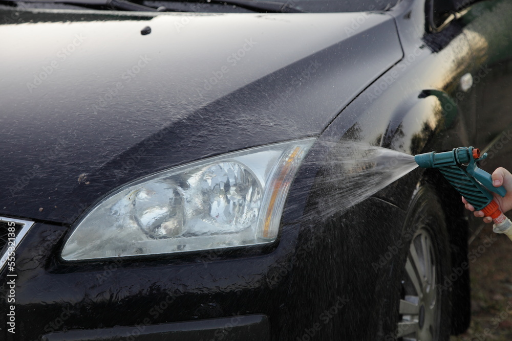 Wet car front washing outdoor with hose Garden gun sprayer in Summer