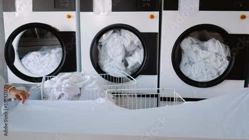 Laundry. Three large washing machines rotate the drums. white linen