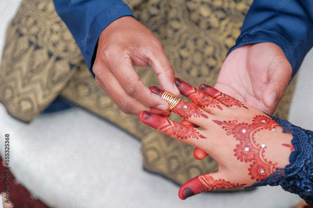 Malay wedding bride put a ring on her bride.