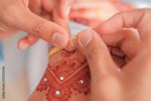 The groom put the wedding bracelet to the bride during solemnization ceremony. Family and happiness concept.