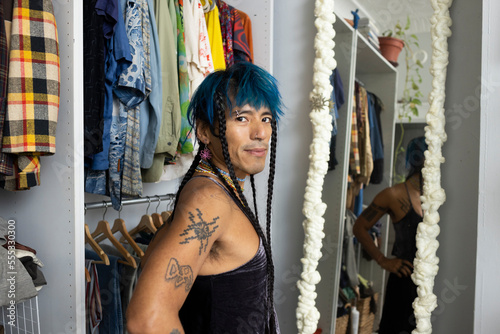 indigenous non-binary artist with blue hair getting dressed