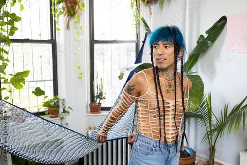 indigenous non-binary artist with blue hair and braids at home photo