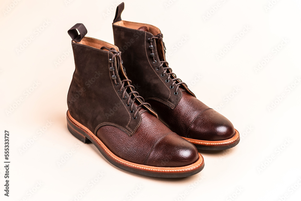 Pair of Premium Dark Brown Grain Brogue Derby Boots Made of Calf Leather with Rubber Sole Placed Over Beige Background.