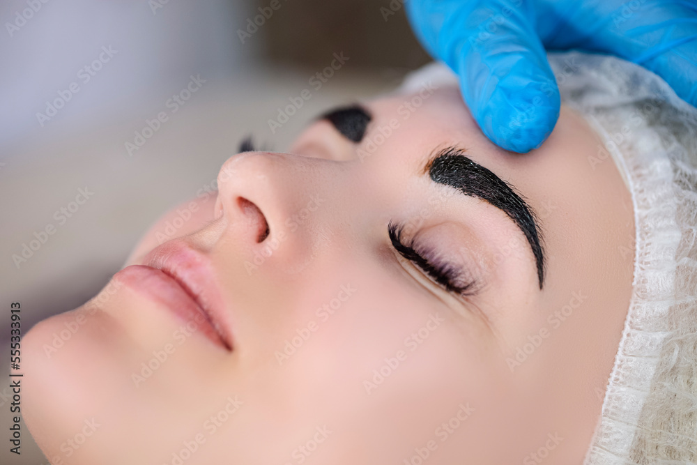 Beauty and Healthy Lifestyle Ideas. Young Beautiful Woman Having Permanent Make-up Tattoo on Eyebrows in beauty Salon