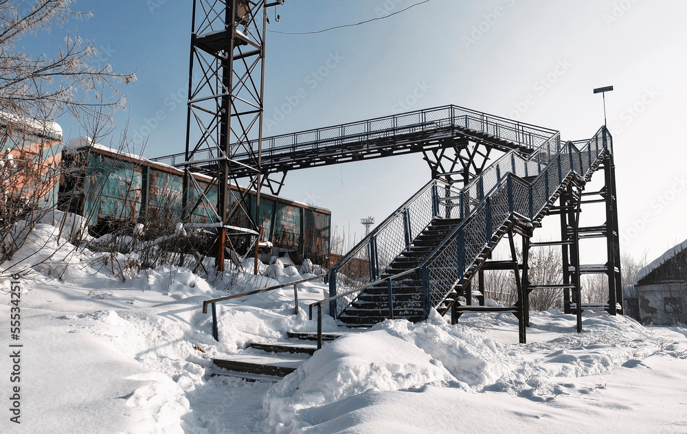 Old pedestrian bridge over the railway. Trains and carriages. Winter, snow. Ust-Kamenogorsk (kazakhstan) Old pedestrian bridge over the railway. Trains and carriages. Winter, snow. Ust-Kamenogorsk (kazakhstan)