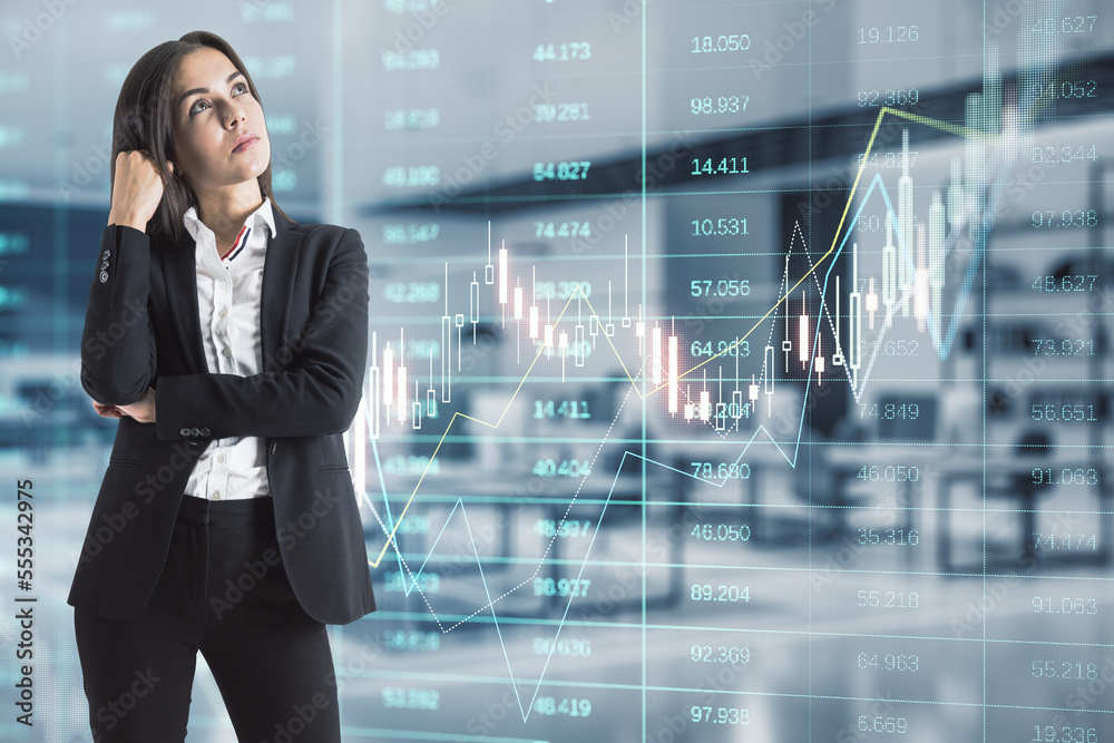 Fototapeta premium Attractive thoughtful young european businesswoman with glowing forex index chart/graph standing in blurry office interior. Trade, finance and market concept. Double exposure.