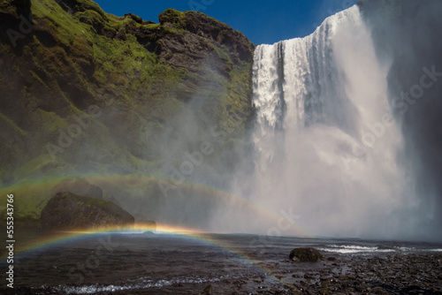 Rainbow near large waterfall landscape photo. Beautiful nature scenery photography with sky on background. Idyllic scene. High quality picture for wallpaper  travel blog  magazine  article