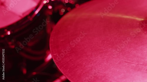 close-up of a musician playing a stick on a hi-hat installation illuminated by pink light, the concept of a rehearsal, concert, repition photo