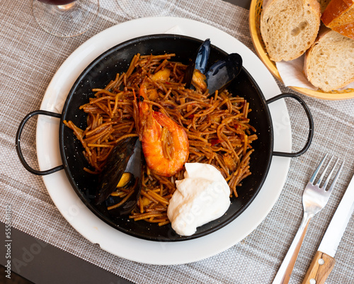 Traditional spanish seafood dish fideua with aioli sauce in a restaurant photo