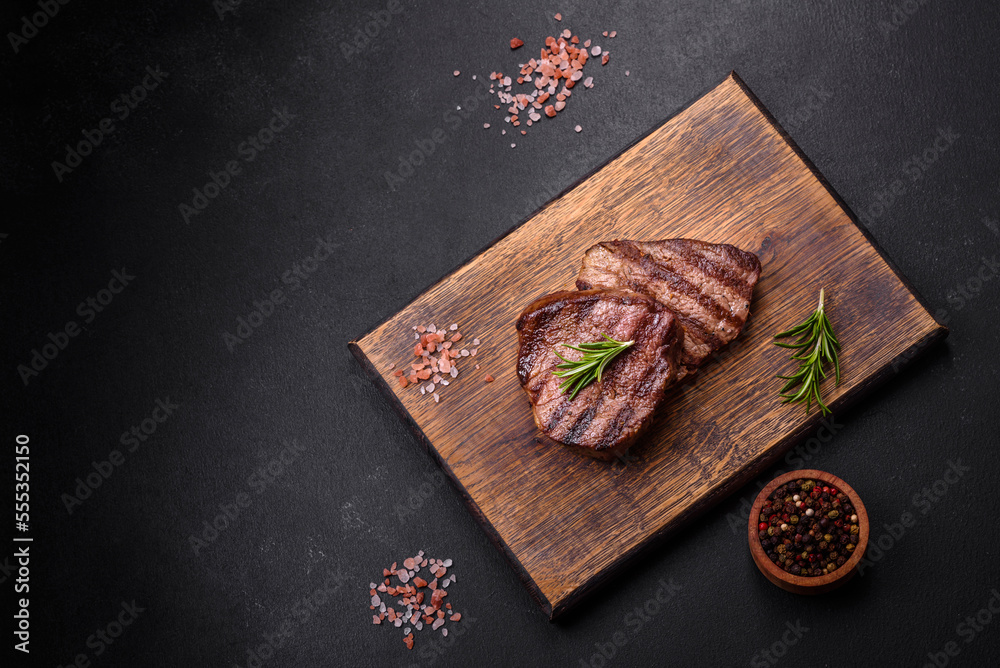 Delicious fresh juicy beef steak with spices and herbs on a dark concrete background Delicious fresh juicy beef steak with spices and herbs on a dark concrete background