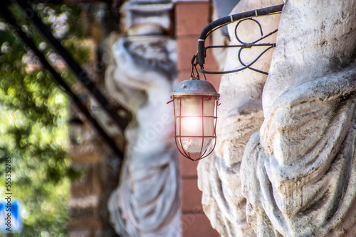 Antique luminous lantern hangs on an ancient sculpture of an ancient building