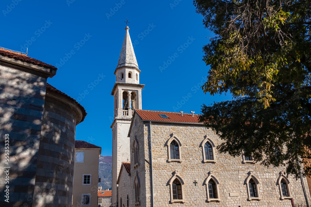 View of white Venetian bell tower in the medieval historic coastal town of Budva, Montenegro, Adriatic Mediterranean Sea, Montenegro, Balkan, Europe. Religious landmark on blue sky background