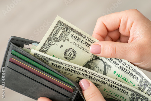 Close up female hands open the wallet and takes dollar banknotes. Financial business, savings and payment concept