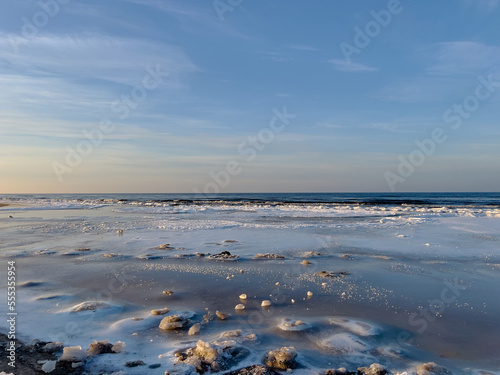 Winter landscape with sea covered with ice and blue clear sky above, selective focus