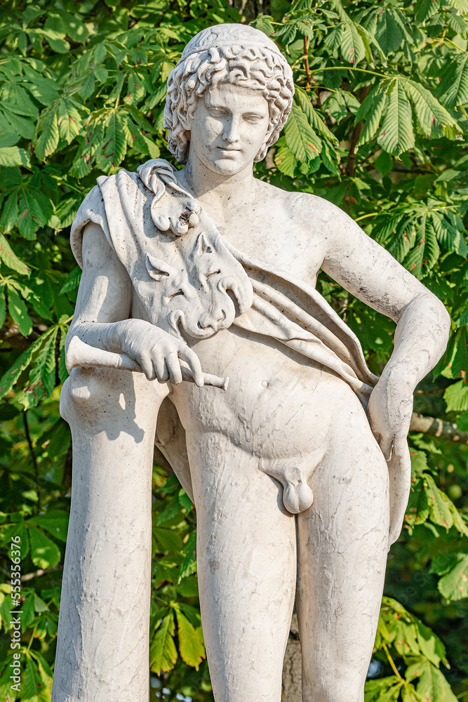 Obraz premium Old park statue of Renaissance Era Roman man hunter in lion skin with hunting tube in city park, Potsdam, Germany