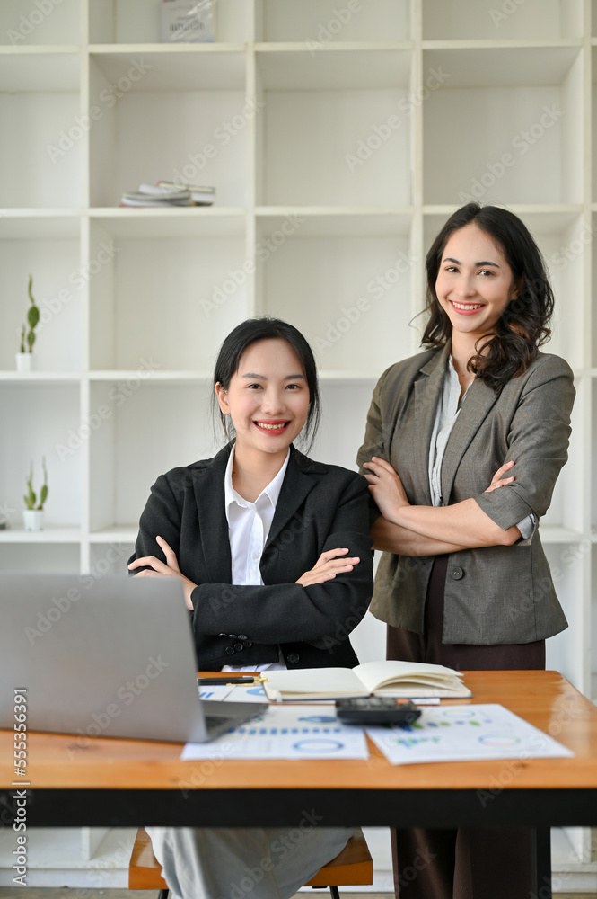 Obraz premium Portrait, Two confident, successful Asian businesswomen in business suits are at the office desk