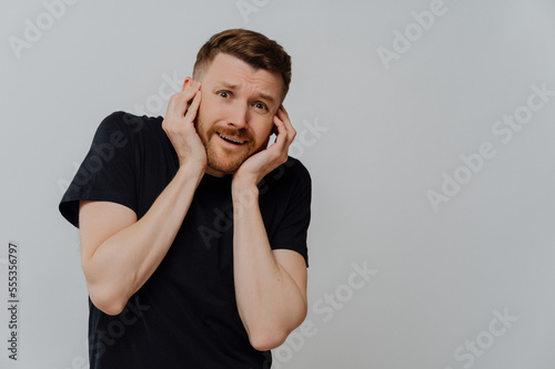 Young nervous man with horrified facial expression being afraid