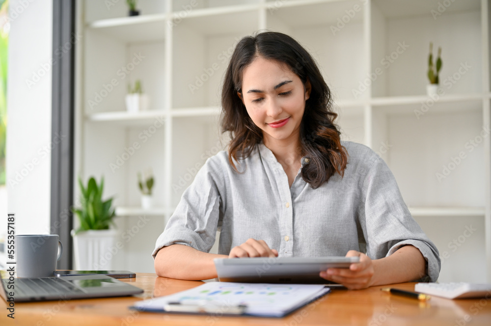 Attractive Asian businesswoman or female manager using digital tablet at her office desk. Attractive Asian businesswoman or female manager using digital tablet at her office desk.