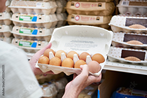 Hands with packages of eggs in store