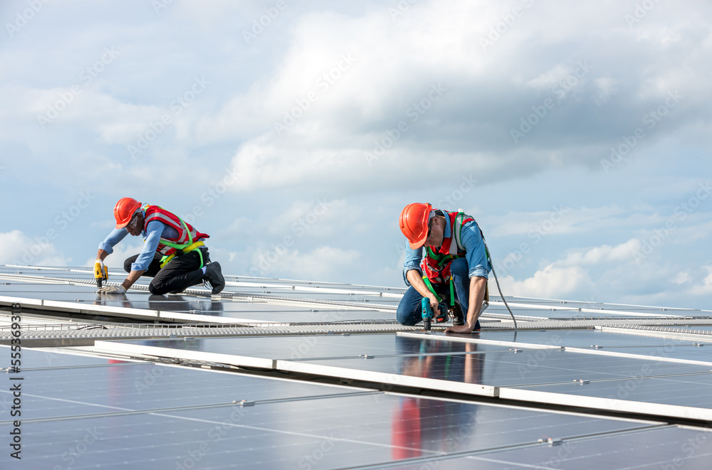 Engineer working setup Solar panel at the roof top. Engineer or worker work on solar panels or solar cells on the roof of business building Engineer working setup Solar panel at the roof top. Engineer or worker work on solar panels or solar cells on the roof of business building