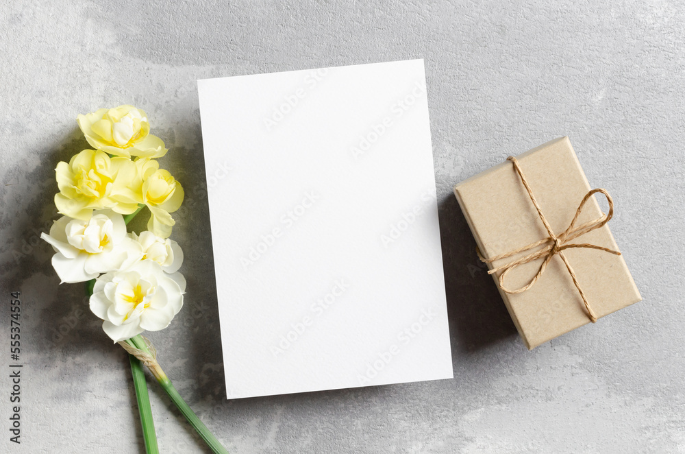 Blank greeting card mockup with gift box and daffodils flowers Blank greeting card mockup with gift box and daffodils flowers